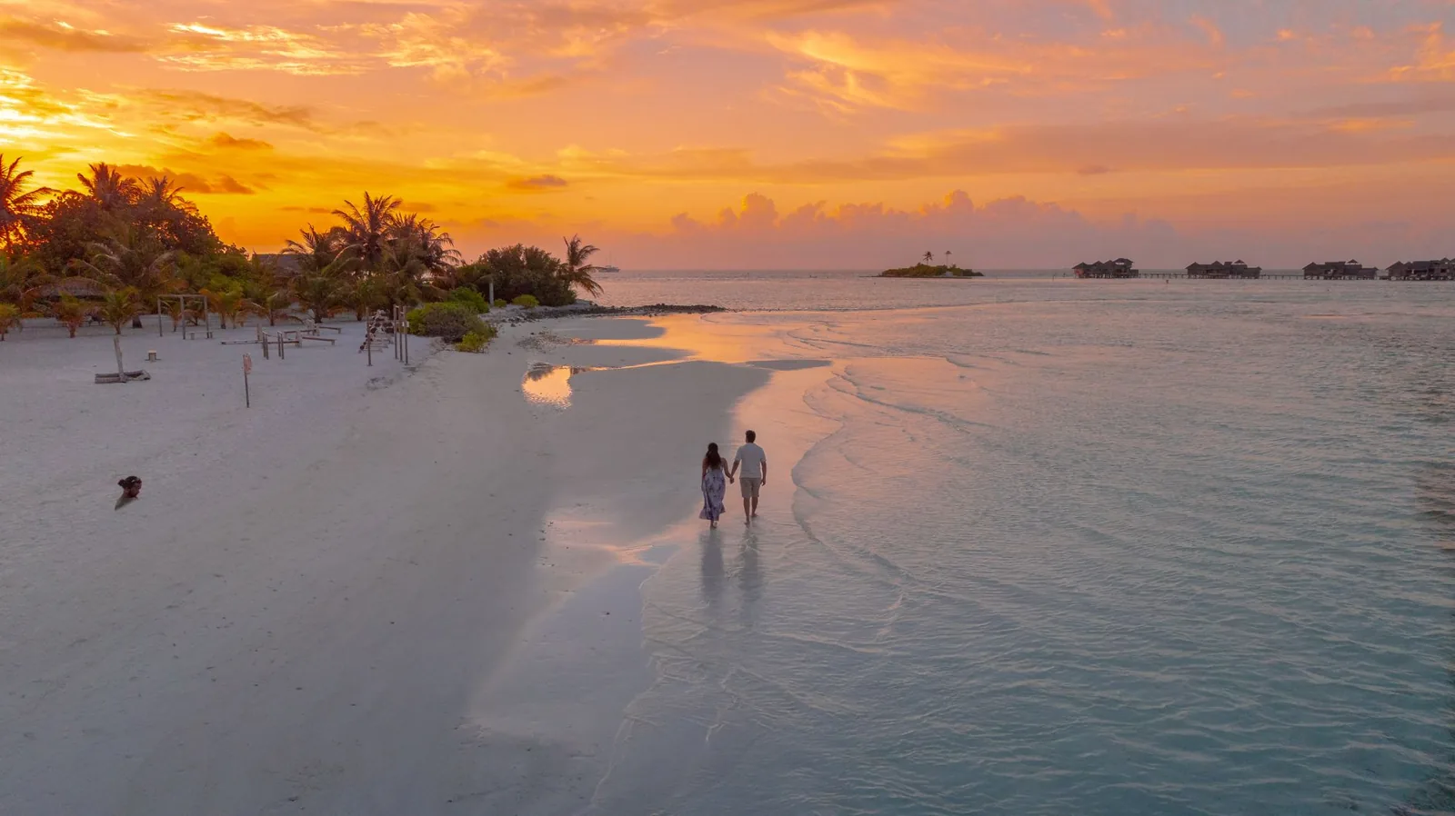best island vacations for couples — couple walking hand in hand on a quiet Caribbean beach at sunrise